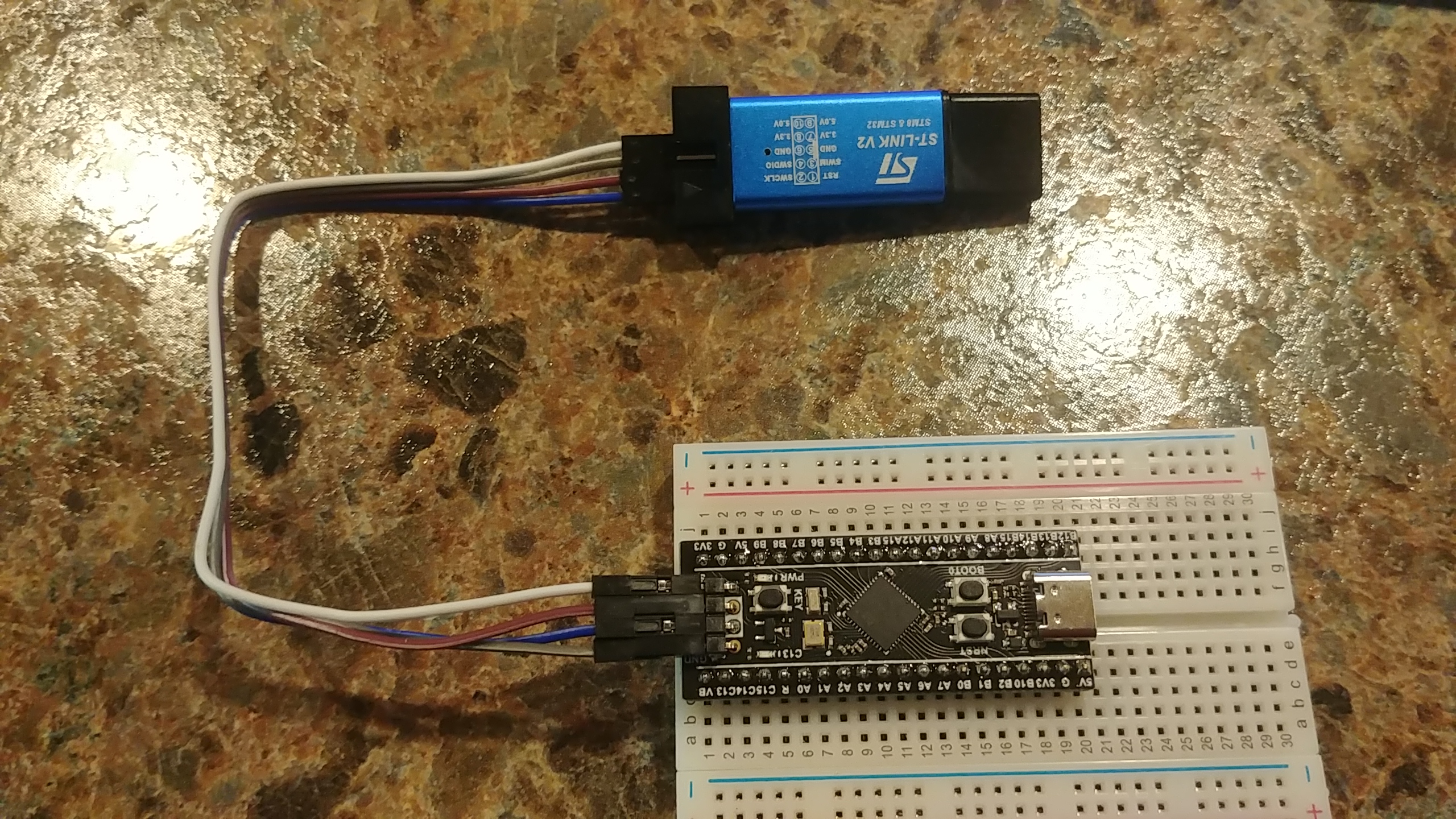 black pill and the st-link are connected with 4 colored jumper wires. the wires connect in the same way listed in the table above